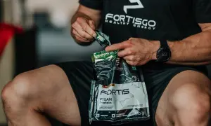 Mężczyzna otwiera opakowanie odżywki białkowej Fortis Vegan Protein. Zastanawiasz się, ile kalorii ma shake proteinowy?