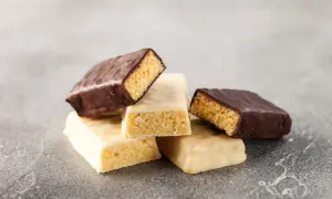 Stos batonów proteinowych, białych i w czekoladzie. Czy baton proteinowy jest zdrowy? Zależy od składu.