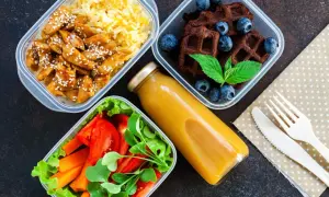 Zdrowe przepisy na lunch do pracy: kurczak z ryżem, sałatka z warzywami, czekoladowe wafle z jagodami i sok.