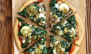 Pizza wegetariańska z cukinią, szpinakiem i pieczarkami, polana sosem pesto.