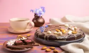 Czekoladowy tort z migdałami i słodkimi kuleczkami, idealny przepis na zdrowy deser. Obok filiżanka kawy i czekoladki.