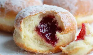 Puszyste pączki z dżemem, posypane cukrem pudrem. Czy pączki są wegańskie? Ten wygląda pysznie!