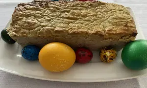 Pieczony pasztet bezglutenowy na białym talerzu z kolorowymi jajkami wielkanocnymi.