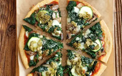 Pizza wegetariańska z cukinią, szpinakiem i pieczarkami, polana sosem pesto.