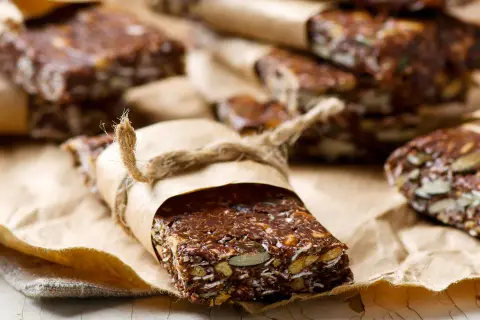 Domowe batony proteinowe z nasionami i bakaliami, zawinięte w papier i przewiązane sznurkiem. Idealne, gdy zastanawiasz się, jakie batony proteinowe wybrać.