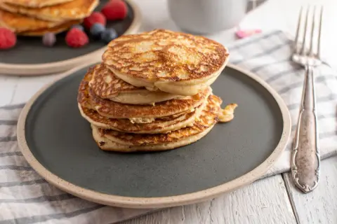 Stos puszystych proteinowych pancakes na talerzu, idealnych na zdrowe śniadanie. Dowiedz się, jak zrobić proteinowe pancakes!