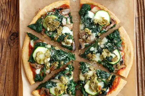 Pizza wegetariańska z cukinią, szpinakiem i pieczarkami, polana sosem pesto.