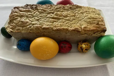 Pieczony pasztet bezglutenowy na białym talerzu z kolorowymi jajkami wielkanocnymi.