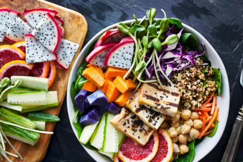 Kolorowa miska pełna zdrowia: grillowane tofu, komosa ryżowa, warzywa i owoce. To właśnie wegańskie co to znaczy – pyszne i odżywcze!