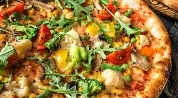 Pizza wegetariańska jakie dodatki? Brokuły, pomidorki, kukurydza, papryka, oliwki, pieczarki i rukola tworzą barwną kompozycję.