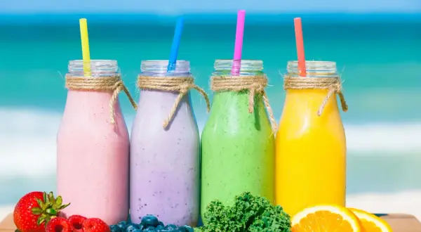 Kolorowe koktajle z blendera na plaży: różowy, fioletowy, zielony i żółty. Idealne przepisy na zdrowe koktajle z blendera.