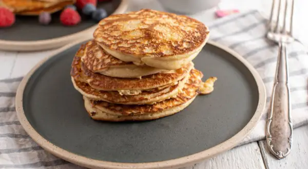 Stos puszystych proteinowych pancakes na talerzu, idealnych na zdrowe śniadanie. Dowiedz się, jak zrobić proteinowe pancakes!