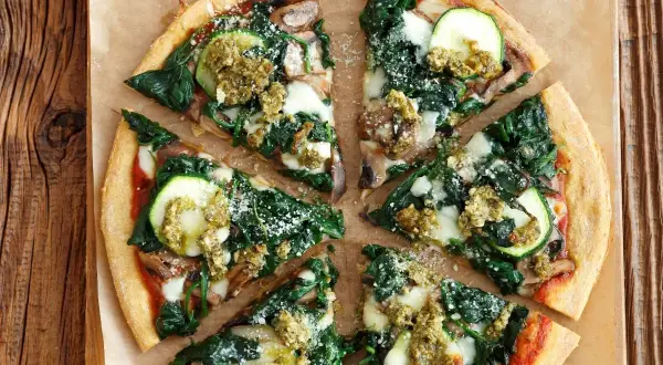 Pizza wegetariańska z cukinią, szpinakiem i pieczarkami, polana sosem pesto.