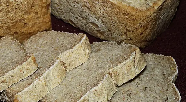 Chleb ryżowy bezglutenowy przepis. Pokrojone kromki domowego chleba ryżowego bezglutenowego na ciemnym tle.
