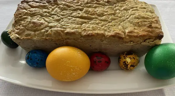 Pieczony pasztet bezglutenowy na białym talerzu z kolorowymi jajkami wielkanocnymi.