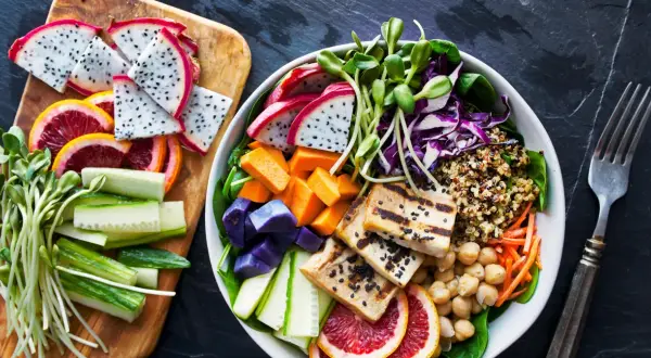 Kolorowa miska pełna zdrowia: grillowane tofu, komosa ryżowa, warzywa i owoce. To właśnie wegańskie co to znaczy – pyszne i odżywcze!
