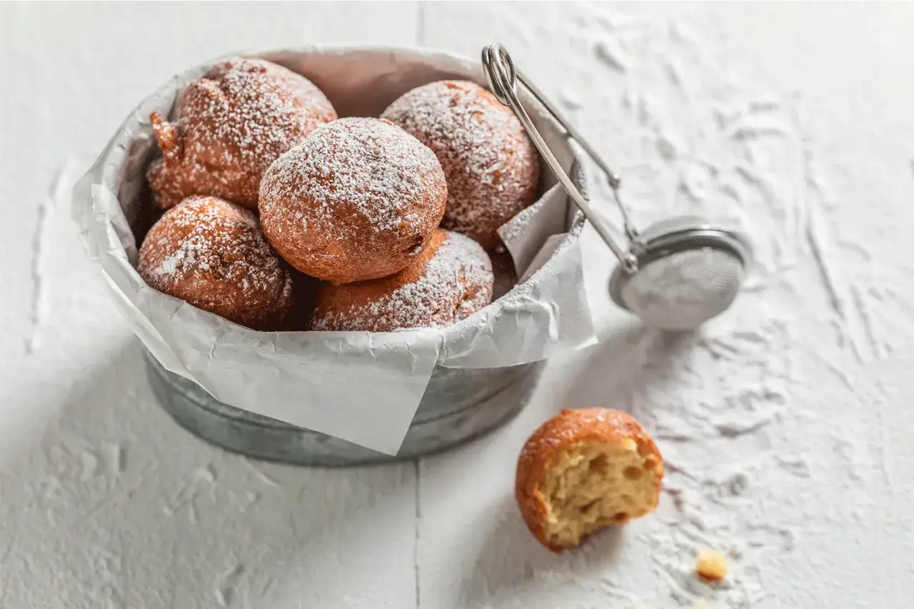 Pyszne pączki bezglutenowe posypane cukrem pudrem, gotowe do jedzenia. Idealne na słodką chwilę.
