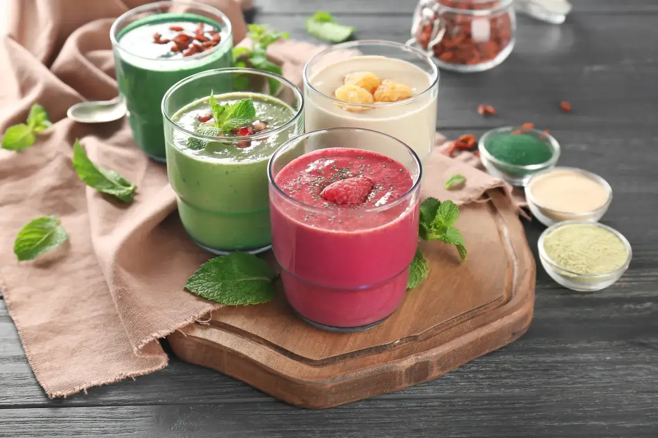 Różowe i zielone koktajle na drewnianej desce. Zastanawiasz się, ile kalorii ma shake proteinowy?