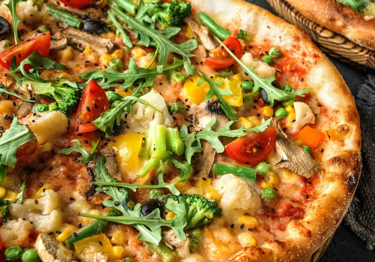 Pizza wegetariańska jakie dodatki? Pełna kolorów: brokuły, pomidorki, kukurydza, papryka, oliwki, pieczarki i rukola.