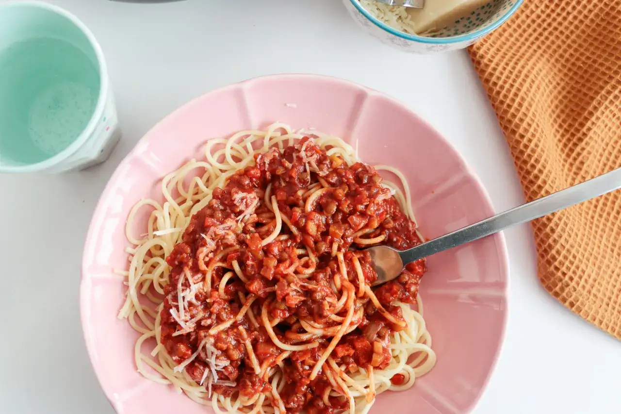 Pyszne wegetariańskie spaghetti z sosem pomidorowym i soczewicą, posypane parmezanem. Idealne, gdy zastanawiasz się, jak zrobić wegetariańskie spaghetti.