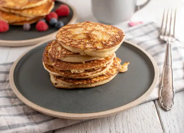 Stos puszystych proteinowych pancakes na talerzu, idealnych na zdrowe śniadanie. Dowiedz się, jak zrobić proteinowe pancakes!